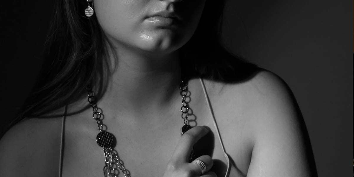 model image in black and white wearing a silver chain and round earrings