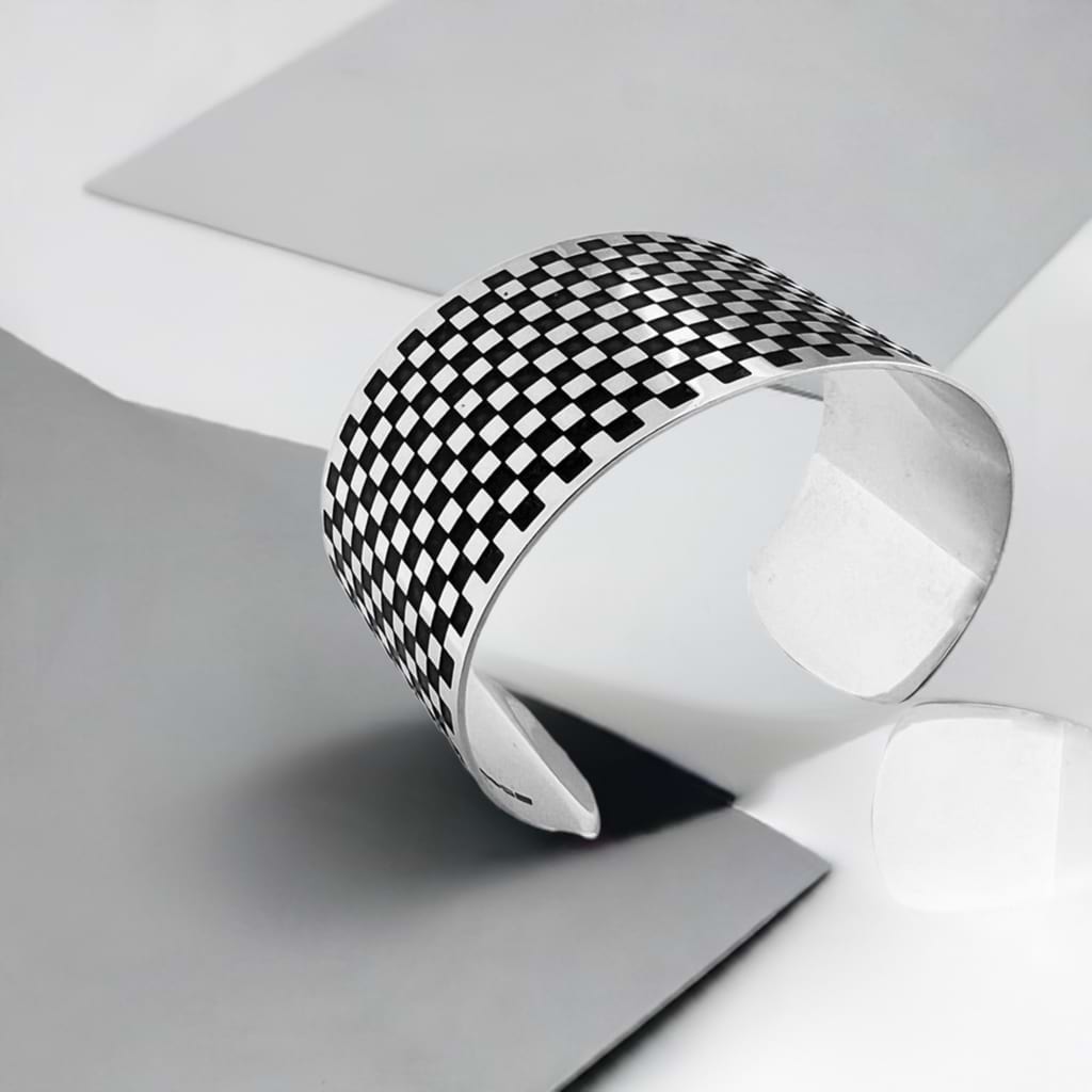 Siver cuff with square pattern with a pastel background