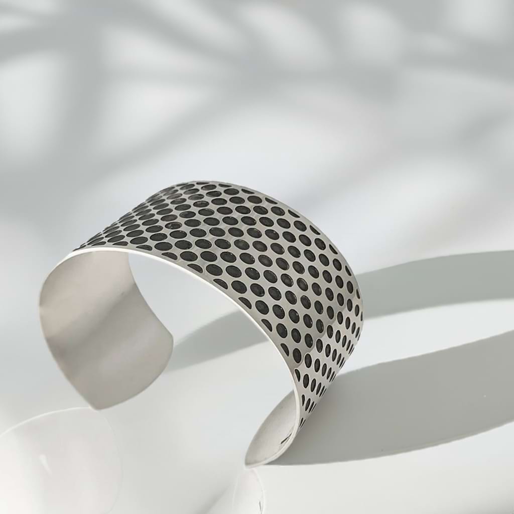 wide cuff bracelet in Silver partly oxidised with a shadow on a white background