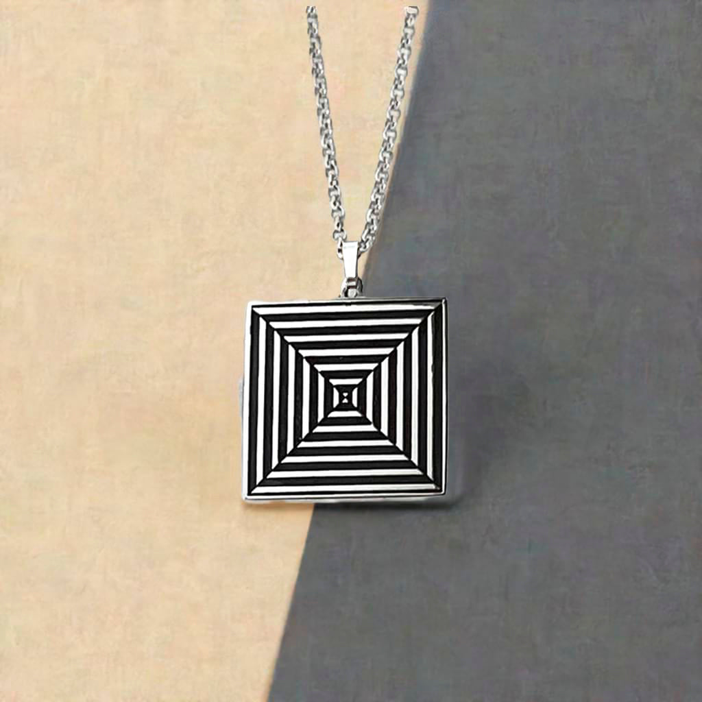 square silver pendant against a two tone background