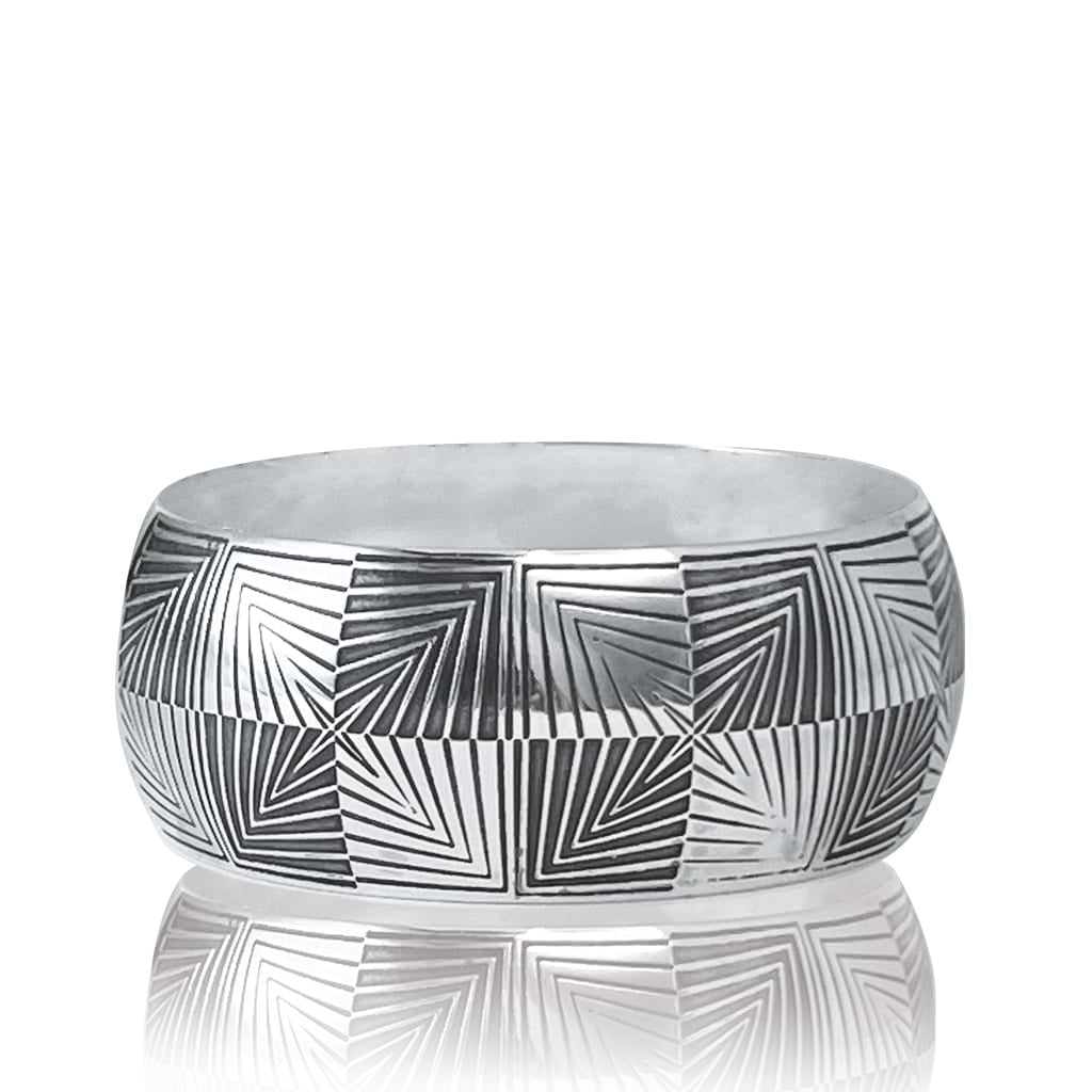 Silver bangle flat on a surface on a white background