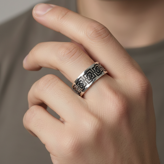 Hand wearing a silver ring with intricate design on a neutral background