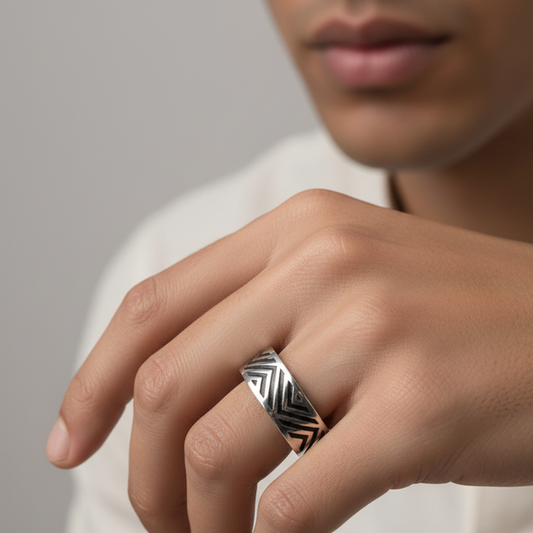 Hand wearing a silver ring with a geometric design on a neutral background