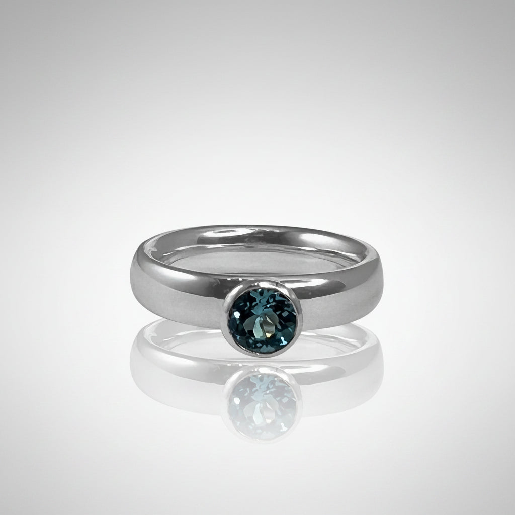 Silver ring with a blue topaz gemstone on a white background