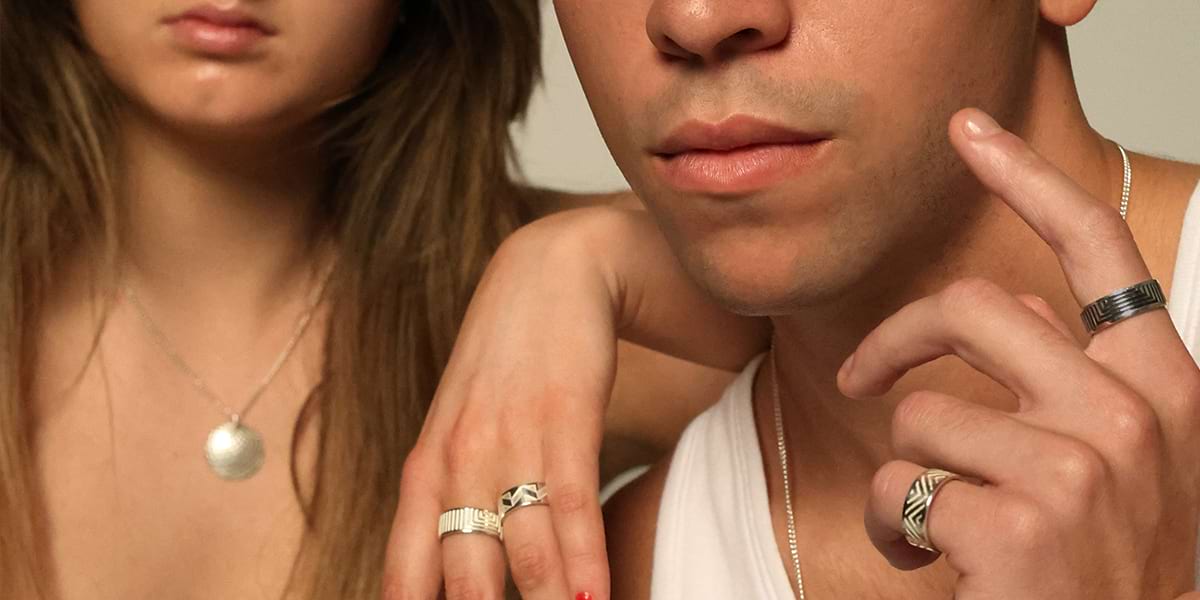 a couple looking at the camera wearing silver unisex jewellery