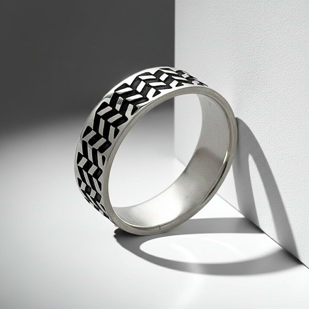 Silver ring with black geometric pattern on a light gray background
