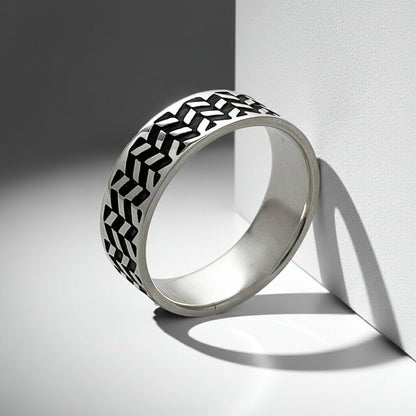 Silver ring with black geometric pattern on a light gray background