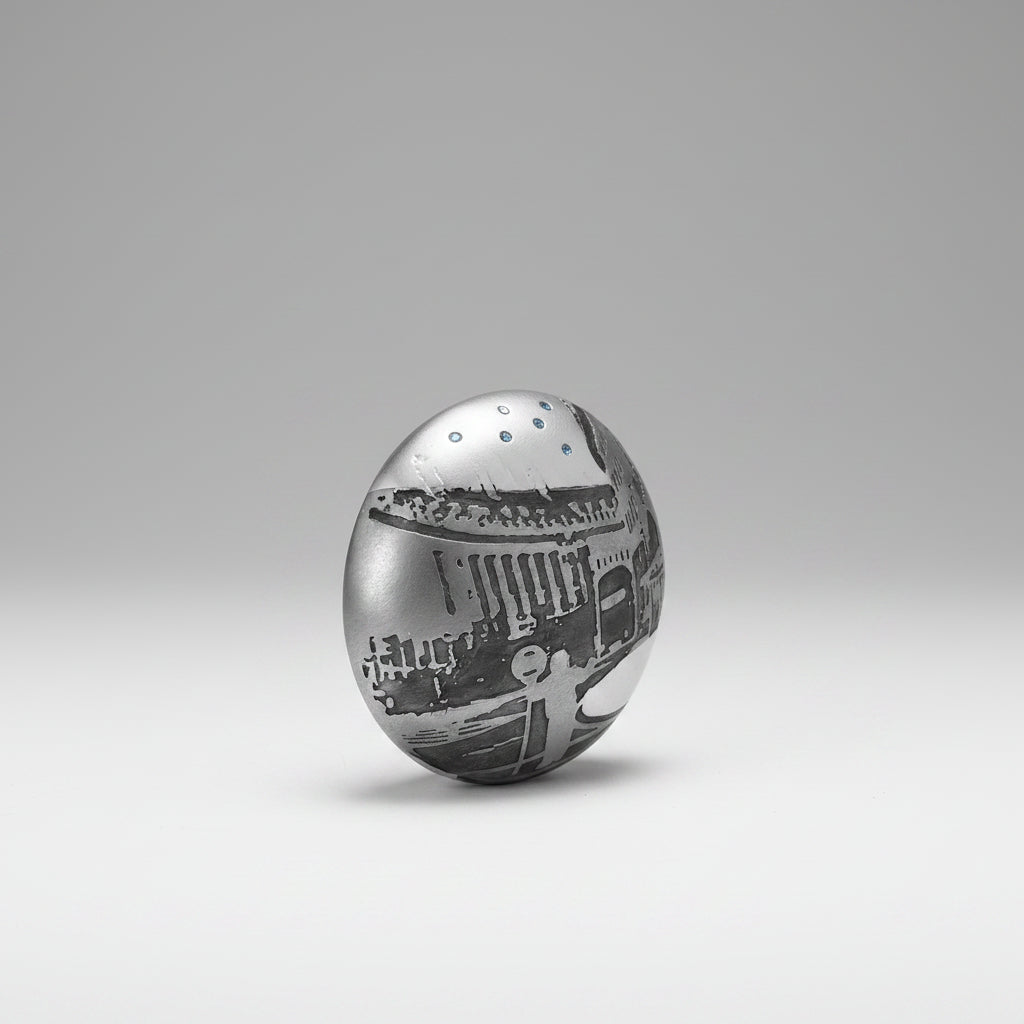 Silver brooch with intricate designs on a white background