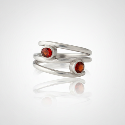 Silver ring with red gemstones on a white background