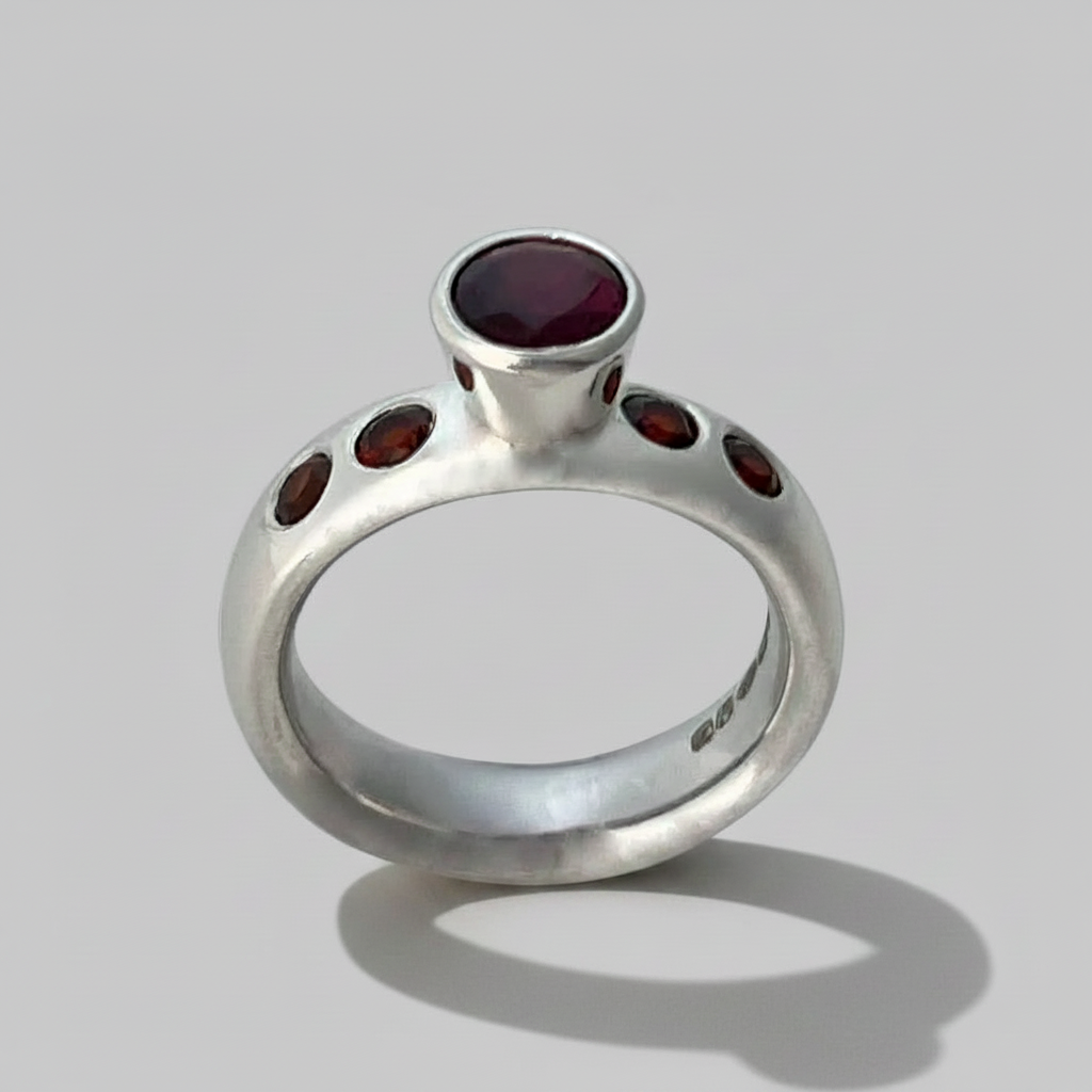 Silver ring with red gemstones on a gray background