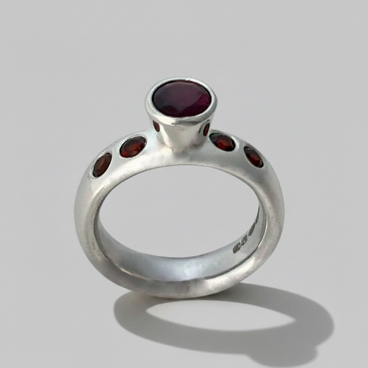 Silver ring with red gemstones on a gray background