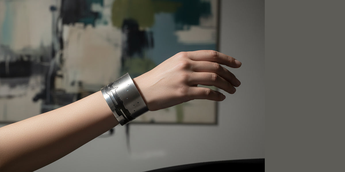 Hand wearing a silver bracelet with a blurred abstract painting in the background