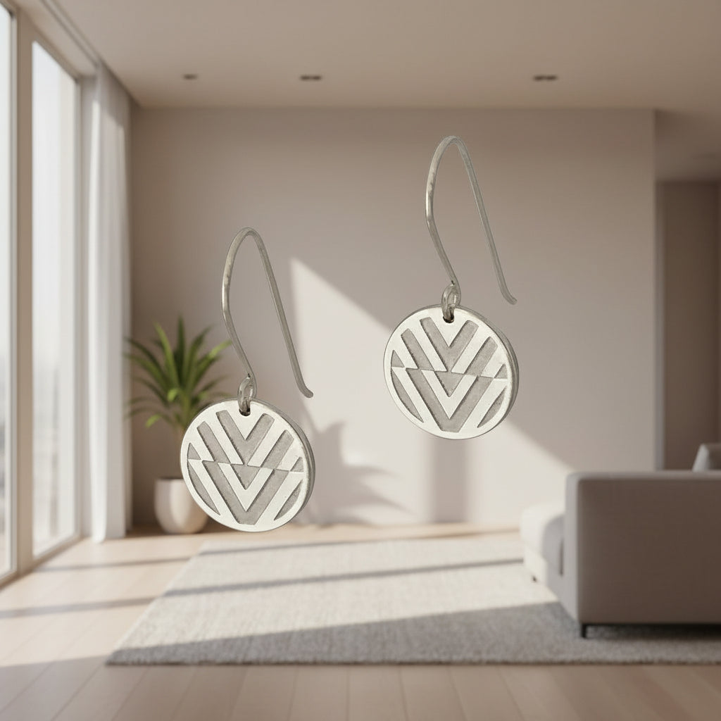 Pair of silver earrings with geometric design on a gray background