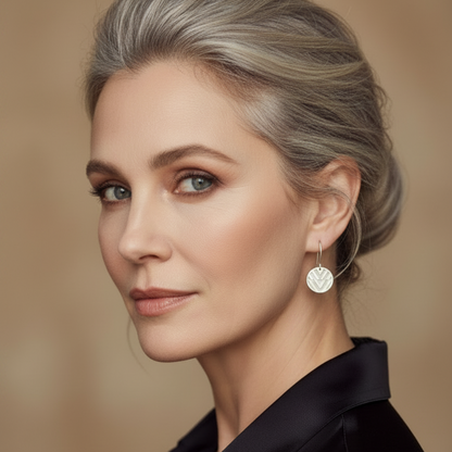 Woman with styled hair wearing earrings against a neutral background