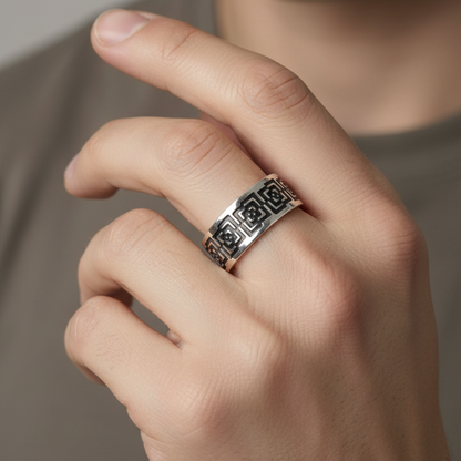 Hand wearing a silver ring with intricate design on a neutral background