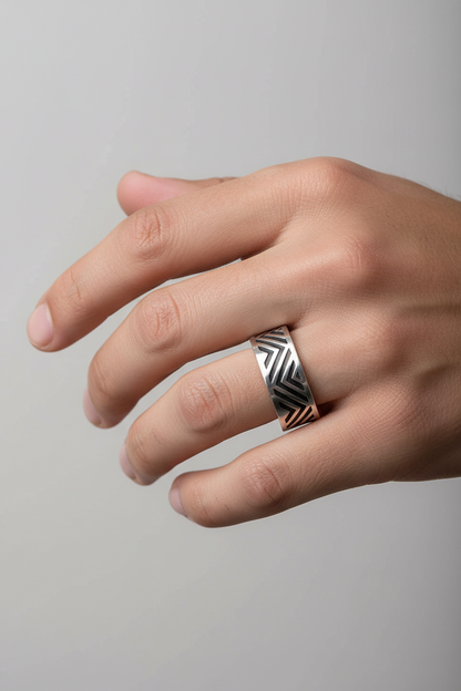 Hand wearing a silver ring with a geometric design on a gray background
