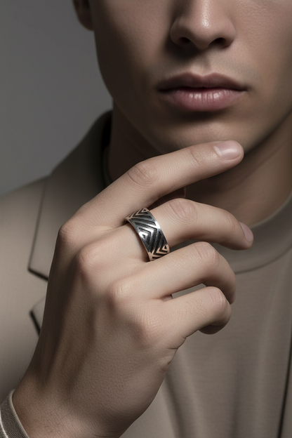 Close-up of a person wearing a ring with a detailed design on a neutral background