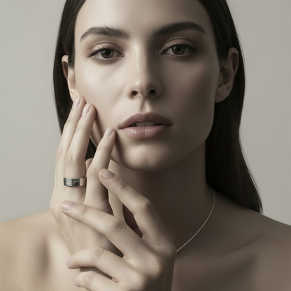 Woman with a ring on her finger touching her face against a neutral background