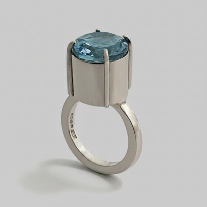 Silver ring with a blue topaz gemstone on a white background