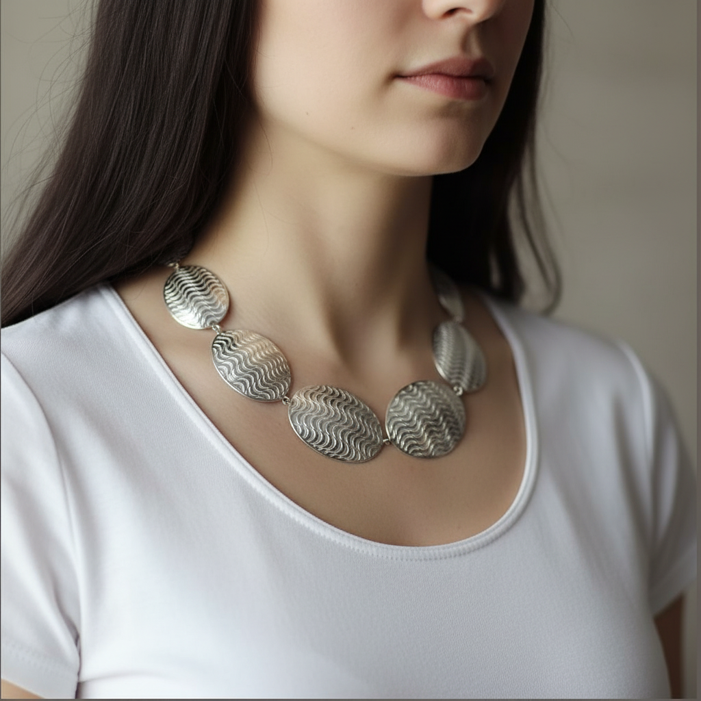 Woman wearing a silver necklace with a plain background