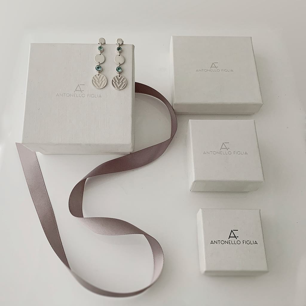 drop earrings laying around jewellery boxes and ribbon