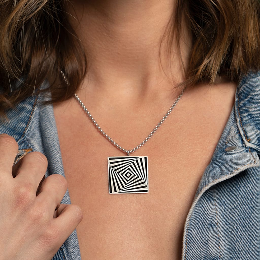 Girl wearing a denim jacket and a silver square pendant on close up