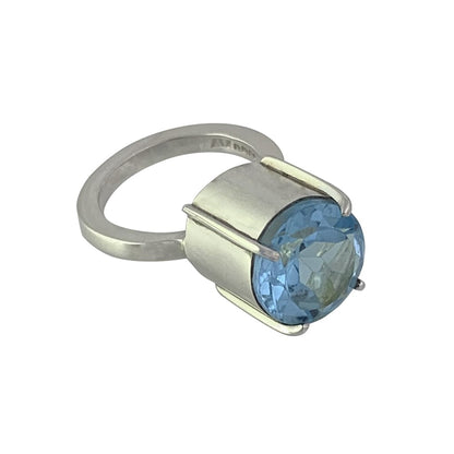 Silver Ring Set with 11mm Blue Topaz Gemstone Lying Flat on a White Background